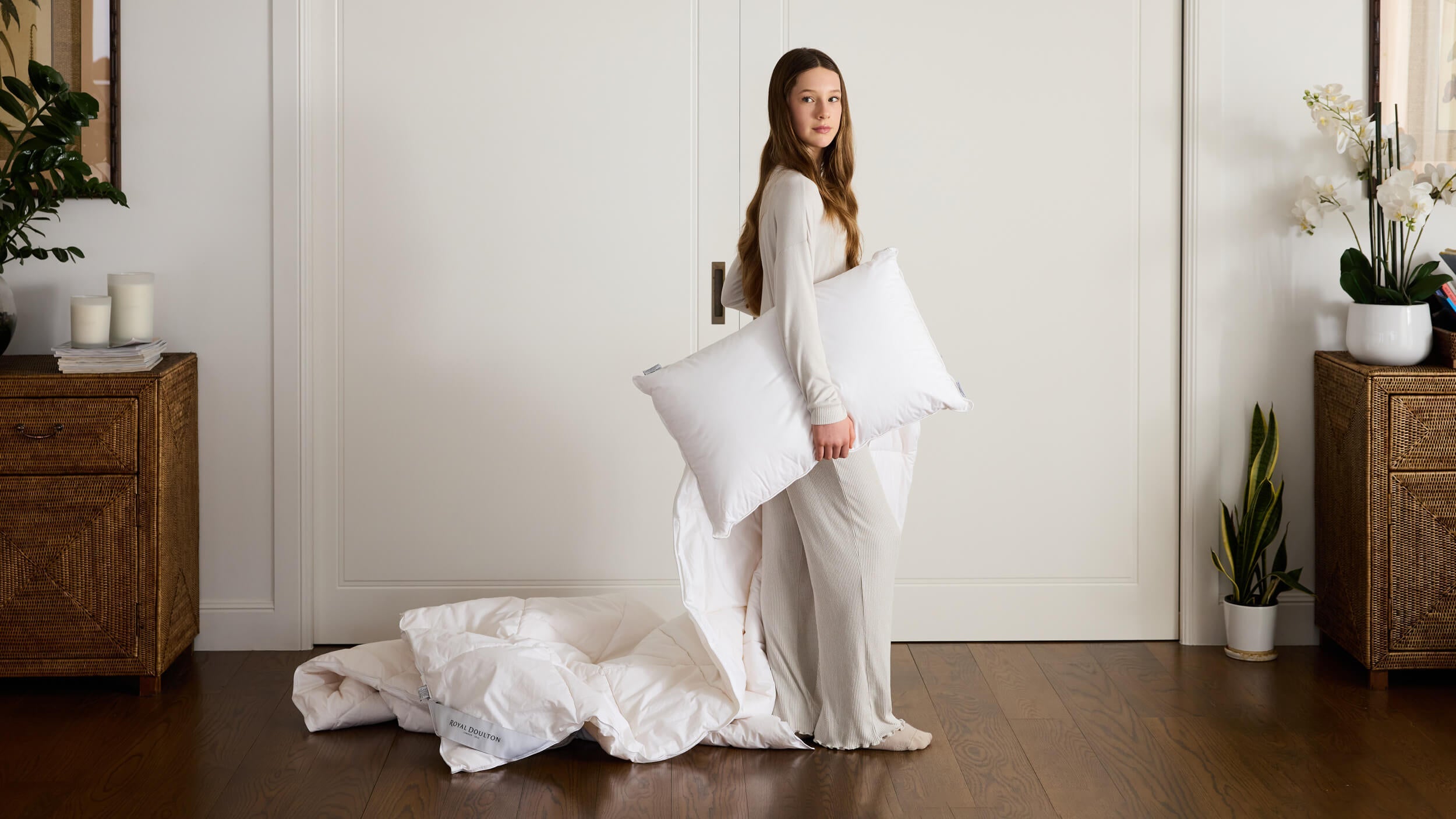 Woman holding a Royal Doulton white pillow beside a duvet inner in a bedroom