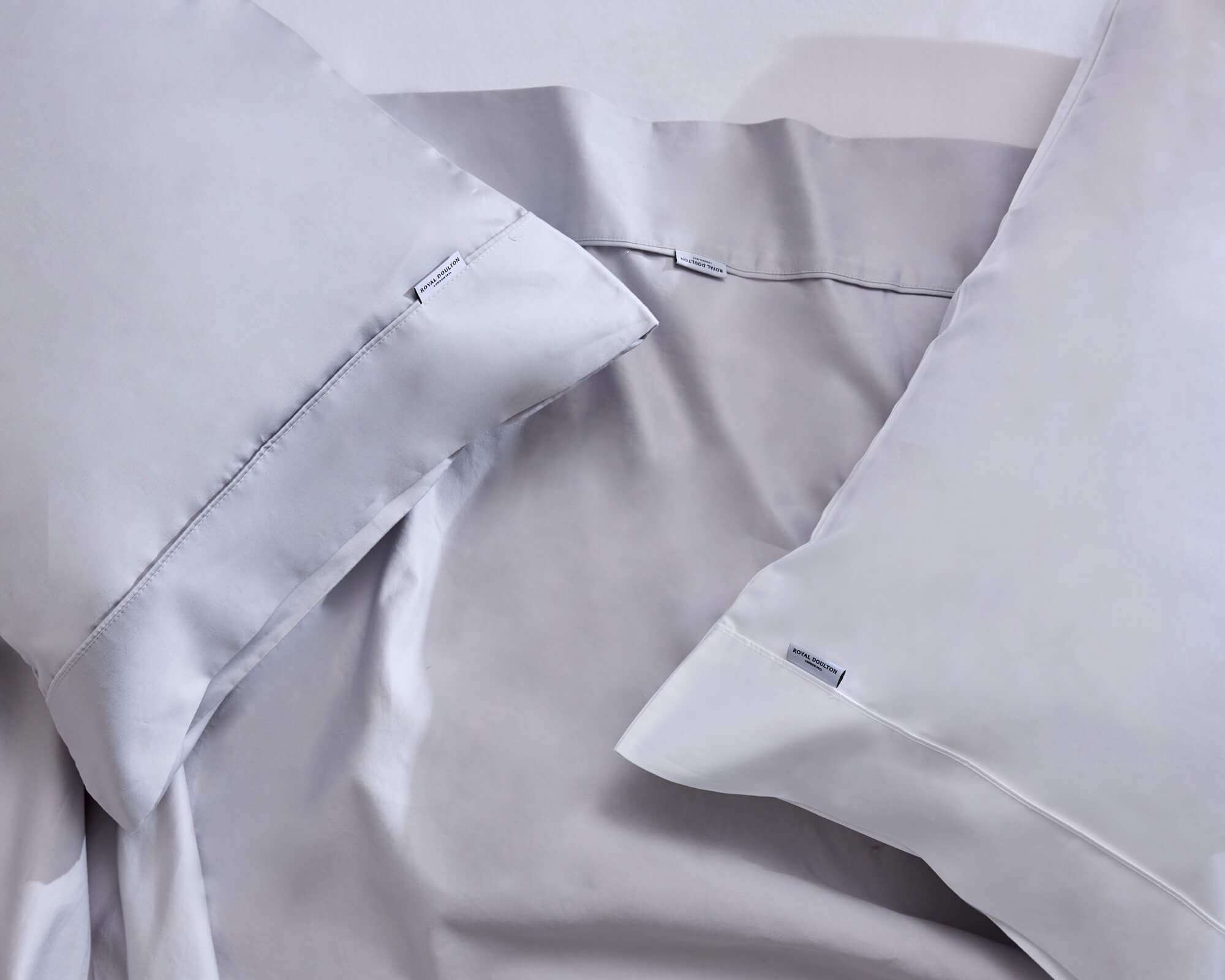 Royal Doulton Aria pale grey sheet set and pillowcases arranged on a bed