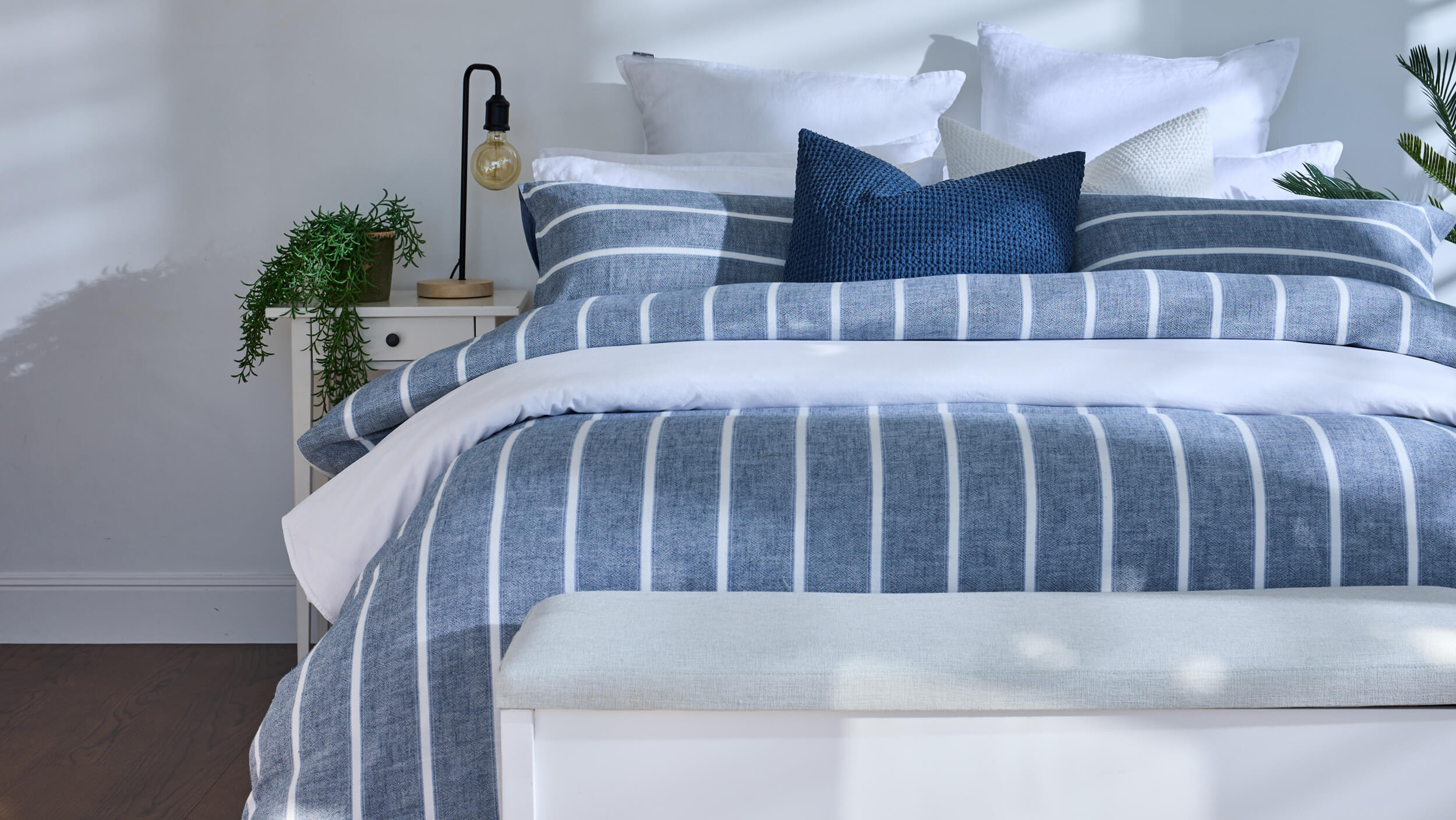 Royal Doulton Kate Nelson blue striped duvet cover on a bed with a navy cushion