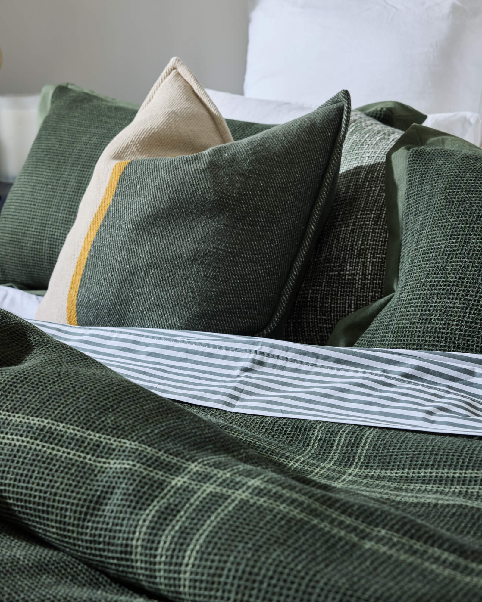 Royal Doulton Hampshire duvet cover styled on a bed with coordinating Levi Printed Sheet, Ellington Cushion, Marlowe Olive cushion.