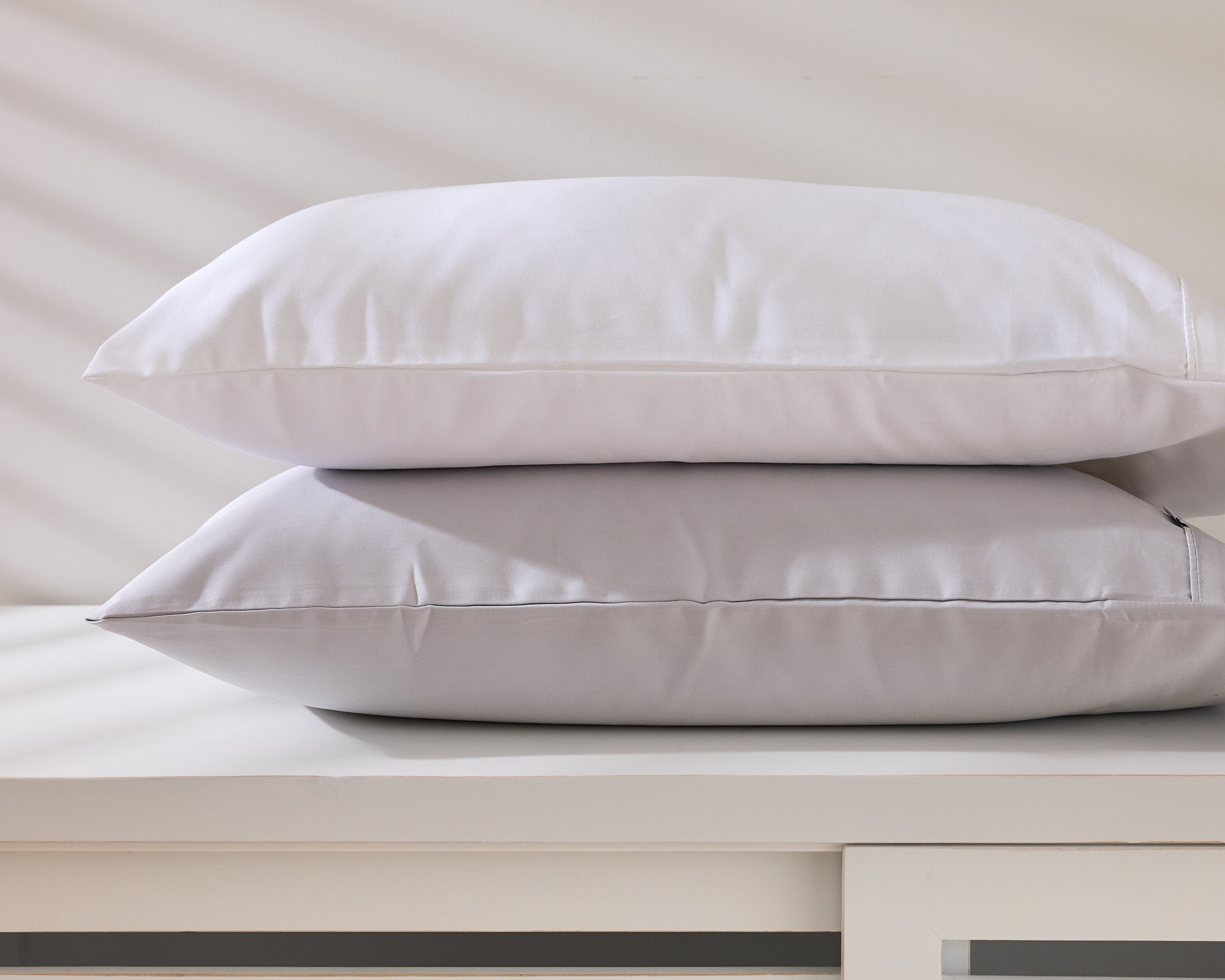 Two white Royal Doulton Aria pillows stacked on a cabinet