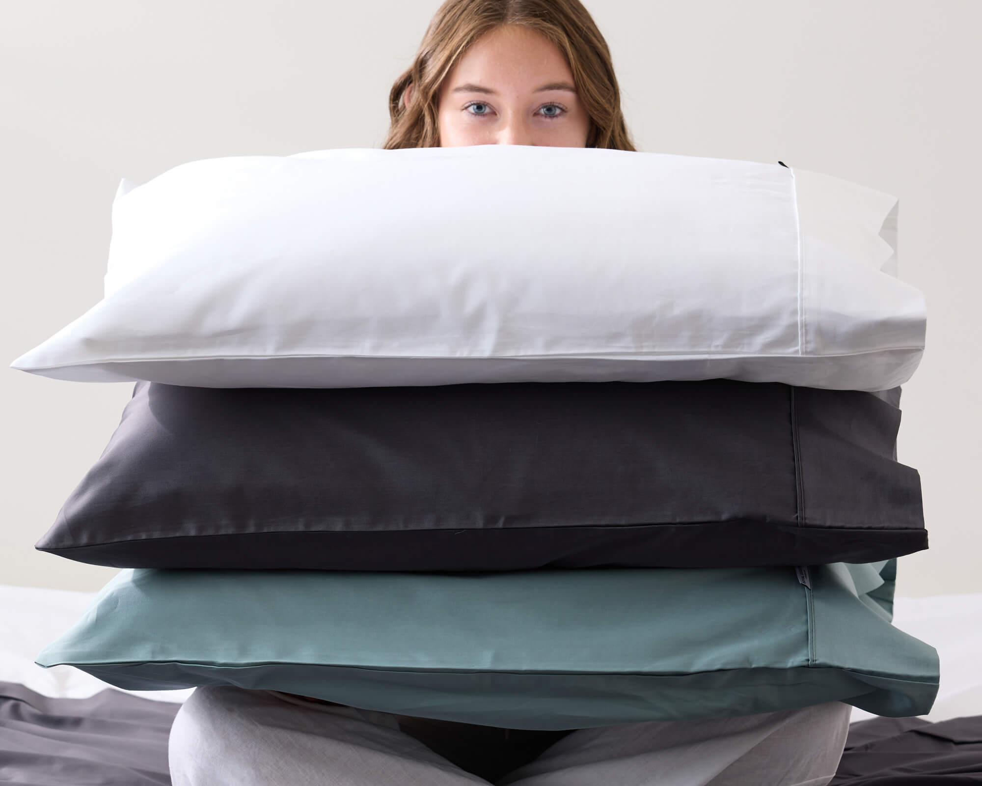 Person holding Royal Doulton Ceilo pillowcases in white, charcoal, sage and grey