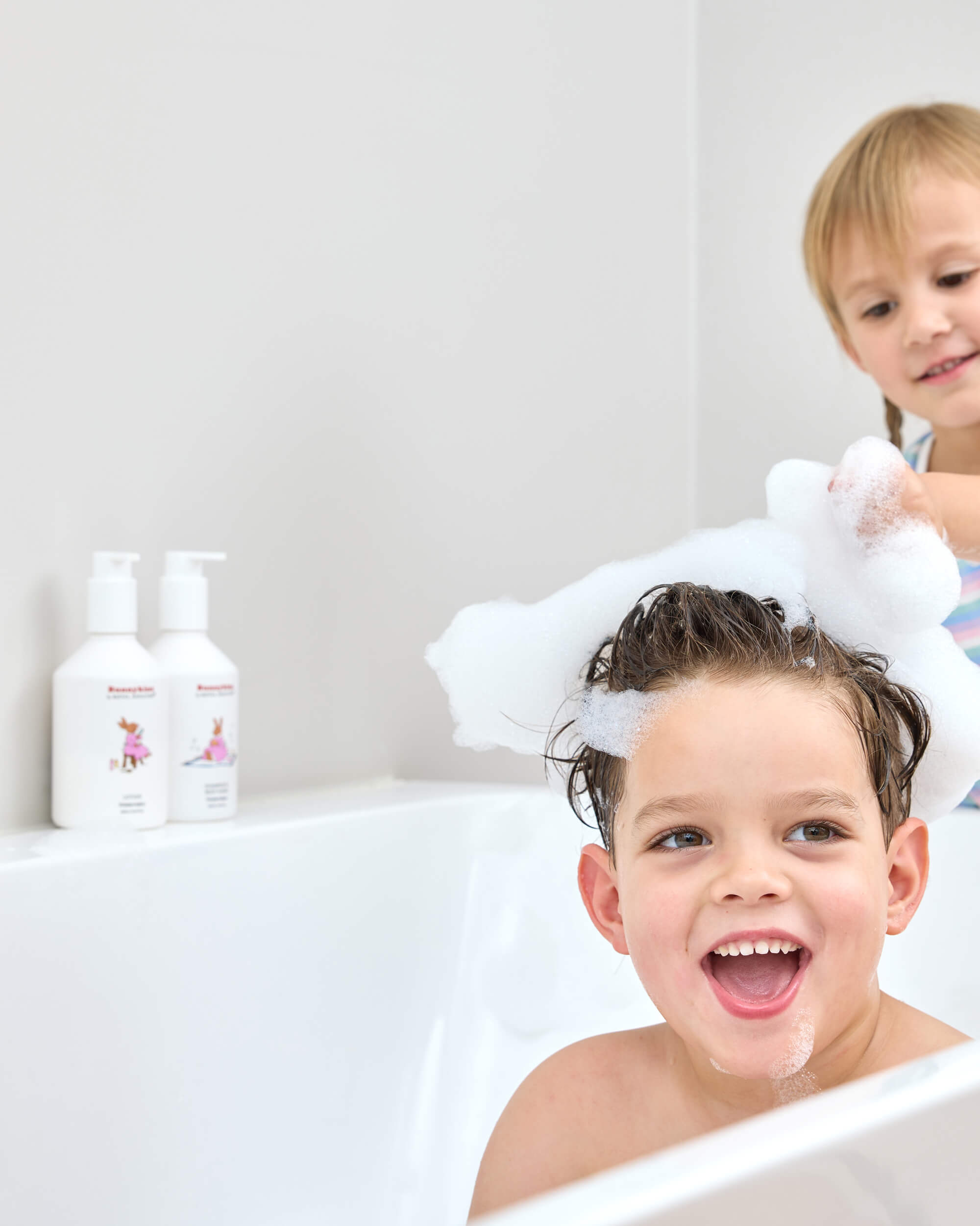 Two children at bath time with Royal Doulton Bunnykins body care bottles