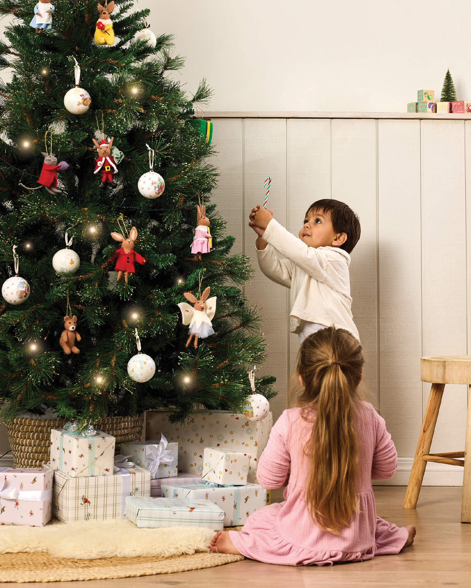 Two children decorating a Christmas tree with Royal Doulton Bunnykins ornaments