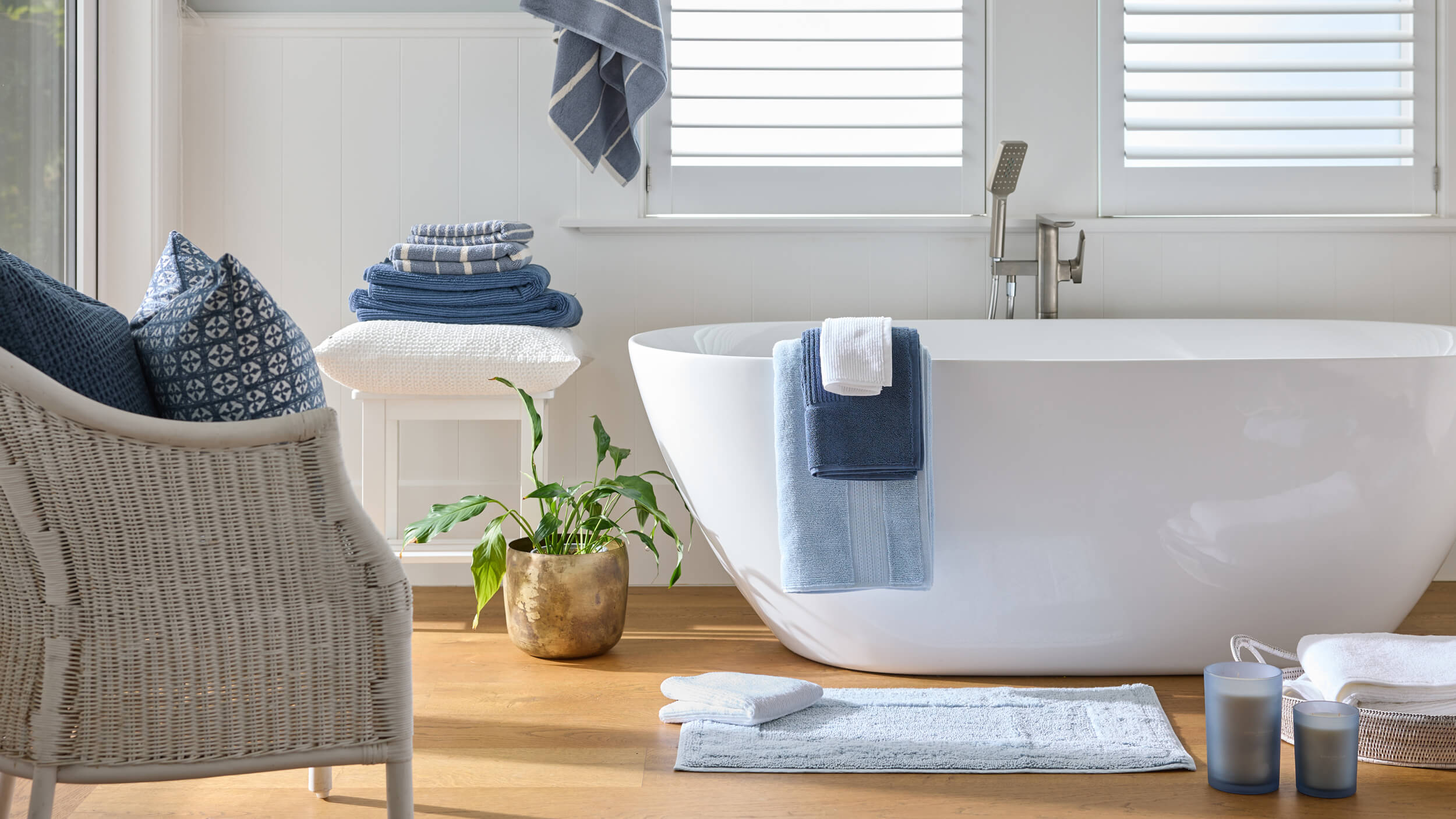 Royal Doulton Renew bathroom with a white freestanding bath, blue towels and a bath mat